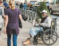 Disabled man seen asking for charity while sitting in his wheelchair as people walk past.