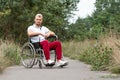 A disabled man sits in a wheelchair on the street. The concept of a wheelchair, disabled person, full life, paralyzed, disabled Royalty Free Stock Photo