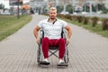A disabled man sits in a wheelchair on the street. The concept of a wheelchair, disabled person, full life, paralyzed, disabled Royalty Free Stock Photo
