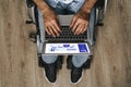 Disabled man sitting in a wheelchair and using laptop Royalty Free Stock Photo
