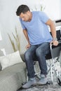 Disabled man trying to sit on sofa Royalty Free Stock Photo