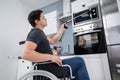 Disabled Man Using Grabber Tool In Kitchen