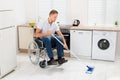 Disabled man on wheelchair cleaning floor