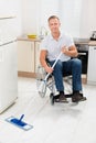 Disabled man on wheelchair cleaning floor