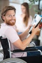 Disabled man in wheelchair girlfriend in background