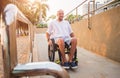 Disabled man in a wheelchair moves on a ramp to the beach. Royalty Free Stock Photo