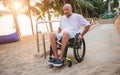 Disabled man in a wheelchair moves on a ramp to the beach. Royalty Free Stock Photo