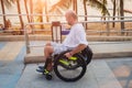 Disabled man in a wheelchair moves on a ramp to the beach. Royalty Free Stock Photo