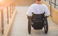 Disabled man in a wheelchair moves on a ramp to the beach. Royalty Free Stock Photo