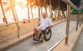 Disabled man in a wheelchair moves on a ramp to the beach. Royalty Free Stock Photo