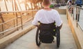 Disabled man in a wheelchair moves on a ramp to the beach. Royalty Free Stock Photo