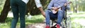Disabled man in wheelchair plays guitar in park passers-by give money. Royalty Free Stock Photo