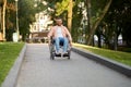 Disabled man in wheelchair rides on a path in park Royalty Free Stock Photo