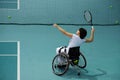 Disabled mature woman on wheelchair playing tennis on tennis court