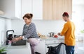 Disabled mature woman in wheelchair talking to son in kitchen indoors at home. Royalty Free Stock Photo