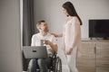 Young man in wheelchair using laptop and girlfriend hugging him at home