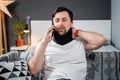 Disabled painful man with neck brace talking on phone at home. Man with spine trauma in neck brace cervical call Royalty Free Stock Photo