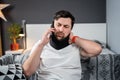 Disabled painful man with neck brace talking on phone at home. Man with spine trauma in neck brace cervical call Royalty Free Stock Photo