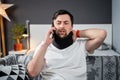 Disabled painful man with neck brace talking on phone at home. Man with spine trauma in neck brace cervical call Royalty Free Stock Photo