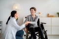 Disabled people healthcare support. Doctor holding hands of handicapped teen boy in wheelchair during medical visit