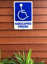 Disabled person parking sign on wooden wall. Blue sign `Handicapped parking` Royalty Free Stock Photo