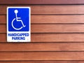 Disabled person parking sign on wooden wall. Blue sign `Handicapped parking` Royalty Free Stock Photo