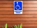 Disabled person parking sign on wooden wall. Blue sign `Handicapped parking` Royalty Free Stock Photo