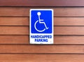 Disabled person parking sign on wooden wall. Blue sign `Handicapped parking` Royalty Free Stock Photo