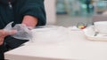 A disabled person puts a plate of food in a plastic bag.