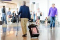 Disabled person walking with stick and luggage in airport