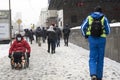 A disabled person in a wheelchair drives on a snow-covered sidewalk