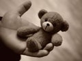 A disabled persons hand holding a raggedy teddy bear symbolizing hope in the face of poverty.. AI generation
