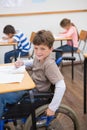 Disabled pupil writing at desk in classroom Royalty Free Stock Photo