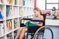 Disabled school girl reading book in library Royalty Free Stock Photo