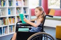 Disabled school girl reading book in library Royalty Free Stock Photo