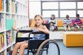 Disabled school girl selecting a book from bookshelf in library Royalty Free Stock Photo