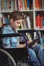 Disabled schoolboy using digital tablet in library Royalty Free Stock Photo