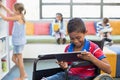 Disabled schoolboy on wheelchair using digital tablet in library