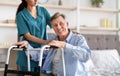 Disabled senior man receiving medical assistance from young caregiver at home, copy space Royalty Free Stock Photo