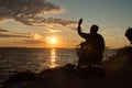 Disabled senior man sitting in wheelchair and using mobile phone during sunset Royalty Free Stock Photo