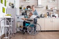 Disabled senior man in wheelchair taking eggs from refrigerator helping his wife Royalty Free Stock Photo