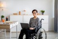 Disabled teen boy in wheelchair doing online homework on laptop indoors Royalty Free Stock Photo