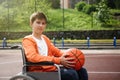 Disabled teenage boy in wheelchair with basketball ball at outdoor court Royalty Free Stock Photo