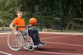 Disabled boy in wheelchair with basketball ball at outdoor court Royalty Free Stock Photo