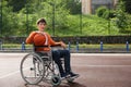 Disabled boy in wheelchair with basketball ball at outdoor court Royalty Free Stock Photo