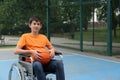 Disabled teenage boy in wheelchair with basketball ball at outdoor court Royalty Free Stock Photo