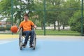 Disabled teenage boy in wheelchair playing basketball  on outdoor court Royalty Free Stock Photo