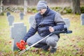 Disabled veteran with crutches near to the tomb monument with flowers