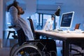 Disabled web developer in the wheelchair works in the office at the computer while performing in co-working space. Disability and Royalty Free Stock Photo