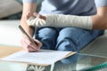 Disabled woman with bandaged arm sigining document Royalty Free Stock Photo